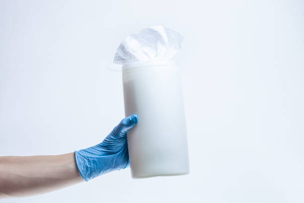 Woman hand wearing protective surgical gloves holds plastic dispenser of wet disinfectant bleach wipes. Products that kill germs and viruses stock photo