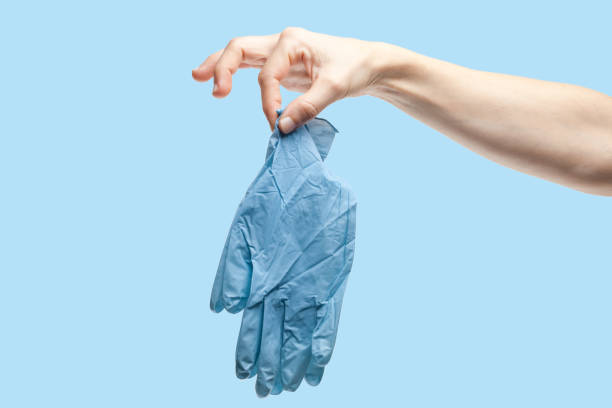 Woman hand holds used surgical gloves in disgust. Disposing of medical protective gloves. Concept of pollution and environmental problems caused by the medical equipment. Contaminated gloves. stock photo