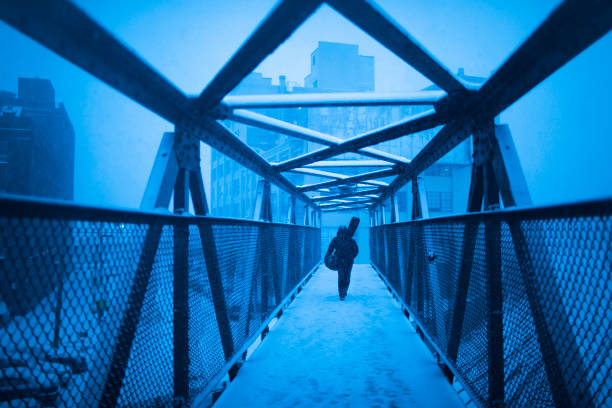 Man Walking down an empty Street in New York city, on a snowy blizzard day with puffy jacket