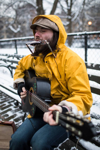 istock Musician sitting on a park bench busking for tips 1222111385