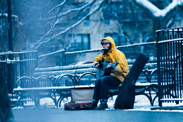Musician sitting on a park bench busking for tips in New York city