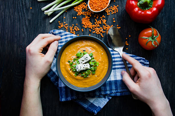 istock Red lentil cream soup decorated with fresh vegetables and herbs. A man eats soup. Veggie concept. Proper nutrition. 1222114047