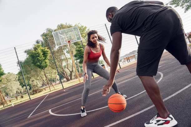 istock Outdoors Activity. African couple guy dribbling back view close-up while girl blocking looking at ball smiling concentrated on basketball court 1222114210