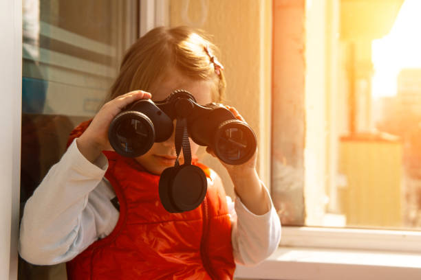 istock A little cute girl on the balcony with binoculars. 1222114268