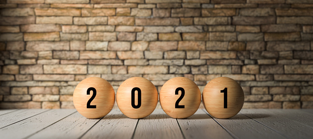 wooden spheres with number 2021 in front of a brick wall on wooden surface - 3D rendered illustration