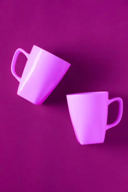 2 isolated pink winter coffee cup mugs for a break time meeting; Copyspace with empty room space for copy text on vertical horizontal background; Girlie female theme