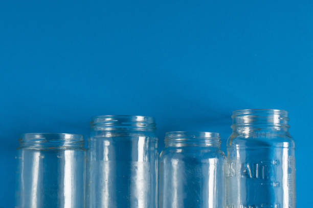 istock 4 several glass jars on an isolated blue background with copyspace or blank empty room space for text or copy. Recyclables for environmental flat lay concept. 1222117134