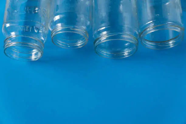 4 several glass jars on an isolated blue background with copyspace or blank empty room space for text or copy. Recyclables for environmental flat lay concept.