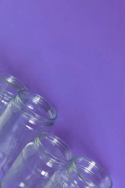 4 several glass jars on an isolated purple background with copyspace or blank empty room space for text or copy. Flat lay concept.