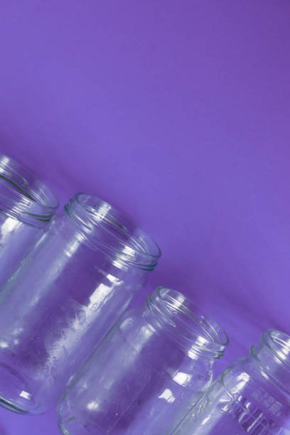 istock 4 several glass jars on an isolated purple background with copyspace or blank empty room space for text or copy. Flat lay concept. 1222117200