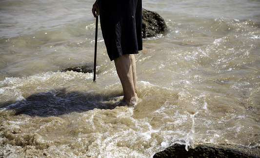 Feet of elderly man on the beach, detail of sport and walk