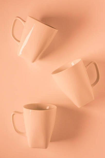 istock 3 monochromatic orange coffee mugs scattered on orange background with blank empty room space for text, copy, or copyspace. Modern top view concept of three several cups with solid background backdrop 1222119262