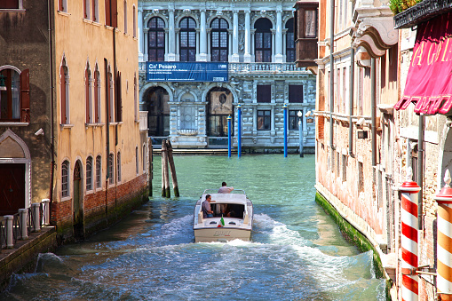 Venice, Italy - June 11, 2017. A Venetian water taxi driving through a canal in Venice.