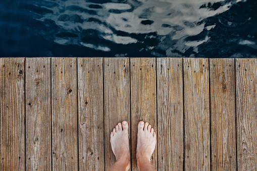 Top angle view of man feet standing on wooden dock at Lake Michigan
