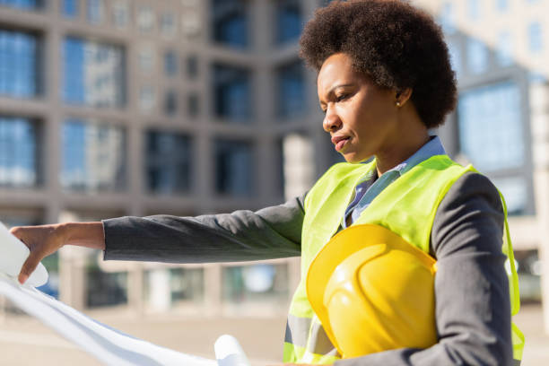 istock Serious female Engineer examining an Office Building Blueprint. 1222132931