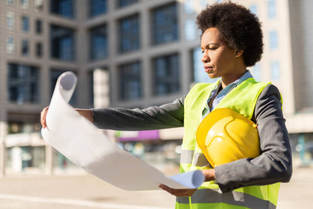 istock Serious female Engineer examining an Office Building Blueprint. 1222132936