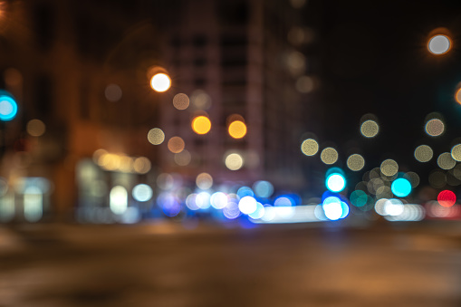 An out of focus cityscape background image of Michigan Avenue in downtown Chicago with red and blue police and ambulance lights at a street corner responding to an emergency blurred in background.