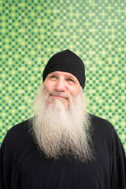istock Mature bearded hipster man with beanie hat thinking against green wall 1222138368