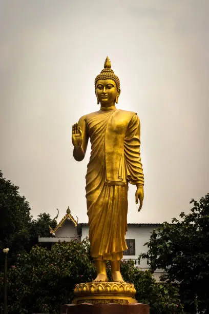 Photo of Budhha young golden standing statue isolated with white sky background