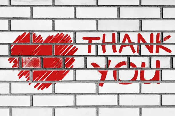 thank you phrase and red heart painted on bricks wall
