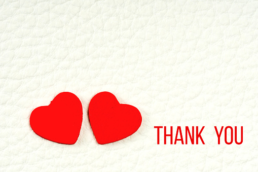 two red wooden hearts and thank you phrase on white leather