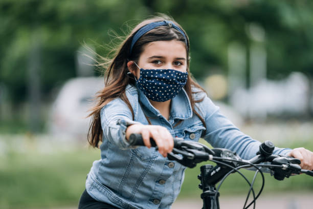 istock Young girl riding a bicycle with a mask 1222149002