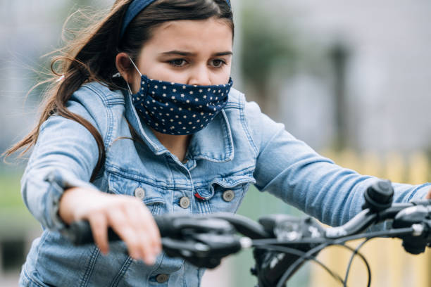 istock Young girl riding a bicycle with a mask 1222149017