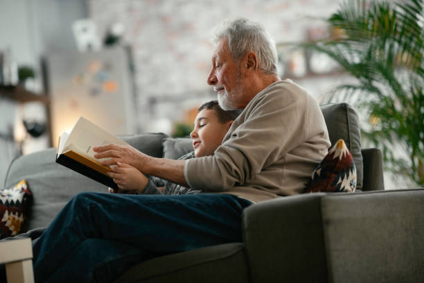 nonno e nipote che leggono libri insieme. - reading book men sofa foto e immagini stock