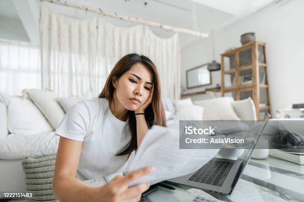 Stressed And Worried Young Asian Woman Working From Home Handling Paperworks And Going Through Her Financials Stock Photo - Download Image Now