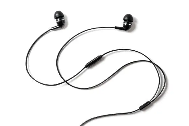 Vacuum black wired earplugs for listening to music and sound on portable devices isolated on a white background. Headphones headset. In-ear headphones for music lovers.