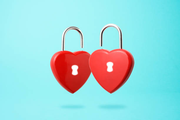 istock Unlocking two red heart shape padlock floating in mid- air. 1222152843