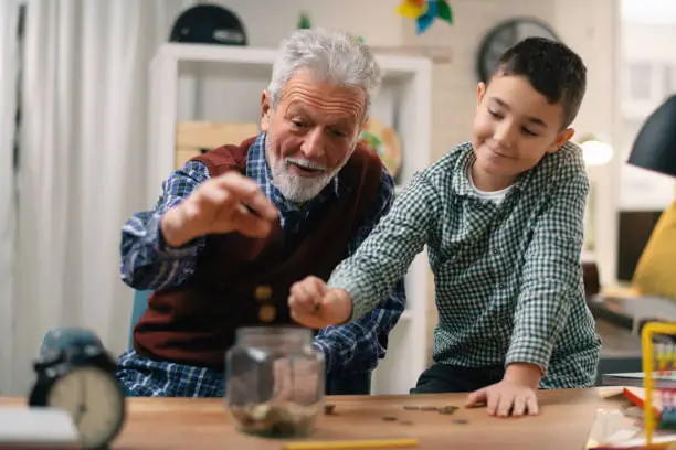 Photo of Grandfather teaching grandchild how to save money.