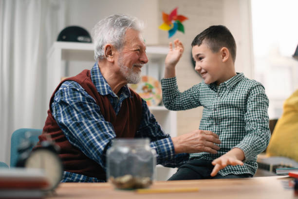 istock Grandfather teaching grandchild how to save money. 1222155809