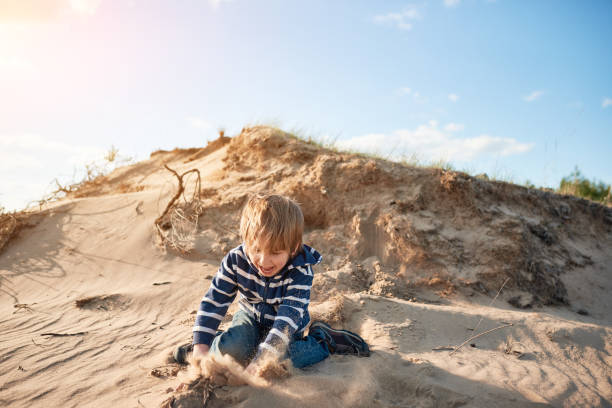 istock Happy boy jumping on sand at sunny day 1222155996