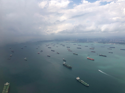 Landscape from bird eye view seascape of dense rows of cargo ship from airplane window. Cargo ships entering one of the busiest ports in the world, Singapore