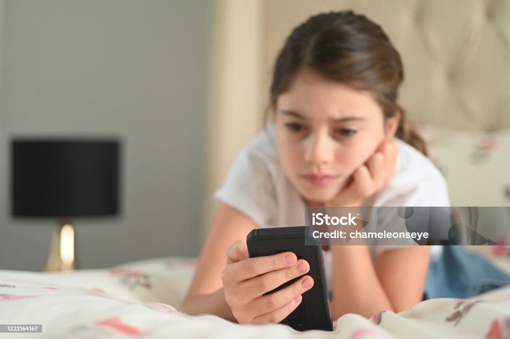 Sad girl reading a bullying post on social media Sad girl (age 10) reading a bullying post on social media. Real people. Copy space Child Stock Photo