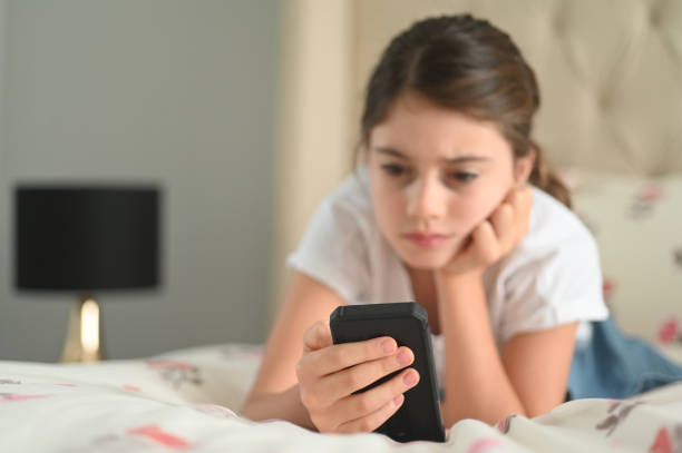 Sad girl reading a bullying post on social media Sad girl (age 10) reading a bullying post on social media. Real people. Copy space social media kids stock pictures, royalty-free photos & images