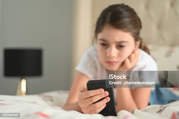 Sad Girl Reading A Bullying Post On Social Media Stock Photo - Download Image Now - Child, Teenager, Adolescence