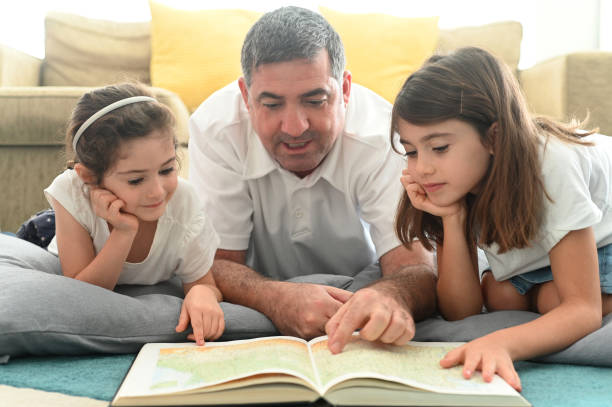 istock Father tutoring daughters in home living room 1222164313