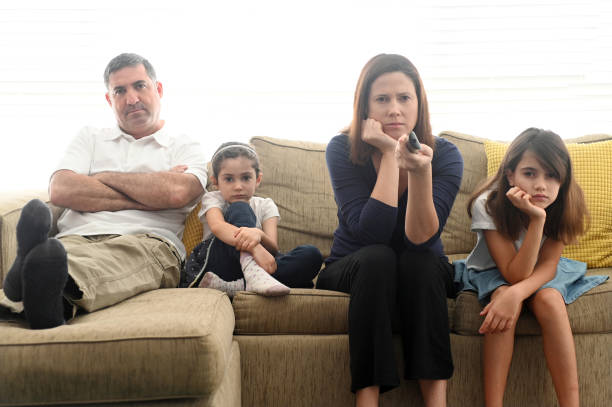 Bored family staring at TV screen Bored family in self quarantine sitting on a couch in home living room staring at TV screen. disappointment photos stock pictures, royalty-free photos & images
