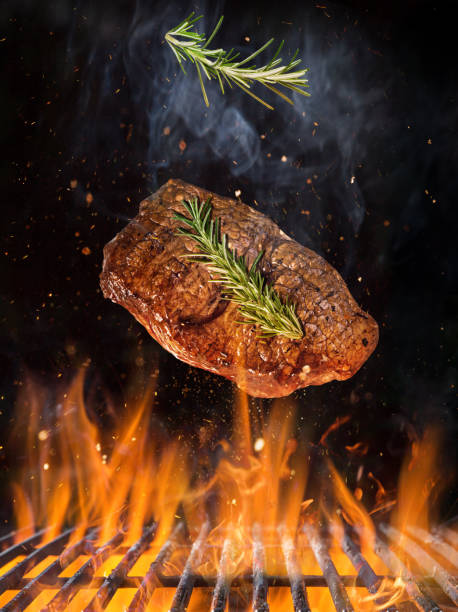 istock Tasty beef steak flying above cast iron grate with fire flames. 1222164444