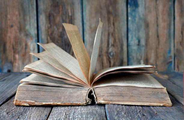 istock Ancient retro book on a wooden background. Text in the book is not recognizable. 1222167399