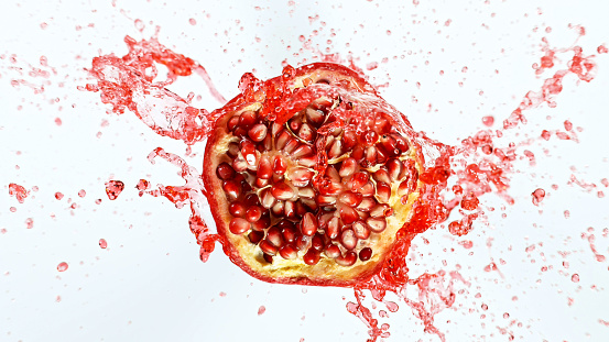Freeze motion of sliced pomegranate with splashing juice.