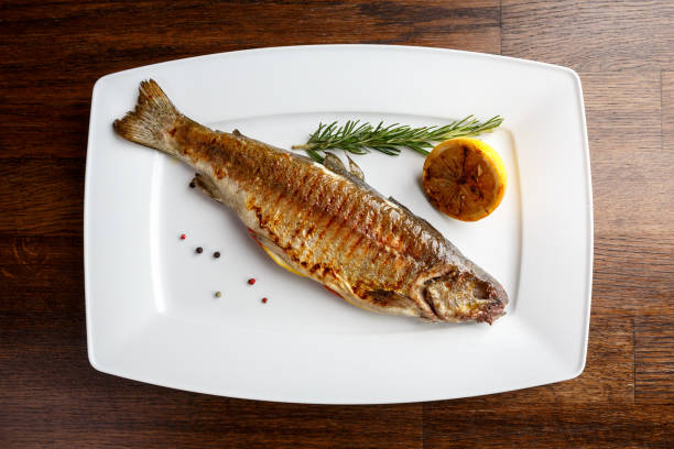 흰 접시에 수제와 레몬을 곁들인 송어 구이 - trout prepared fish whole grilled 뉴스 사진 이미지