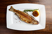 Grilled trout with resemary and lemon served on a white plate