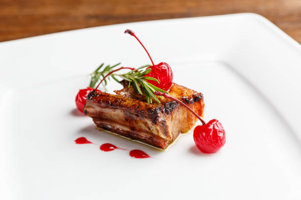 istock Grilled pork ribs decorated with rosemary and caramelized cherry served on a white plate 1222171105