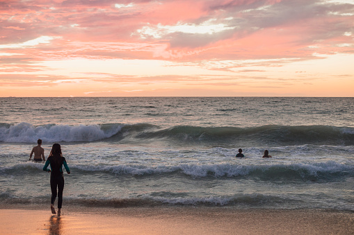 A family take a dip in the beautiful sea st sunset on the beach in Perth Australia.