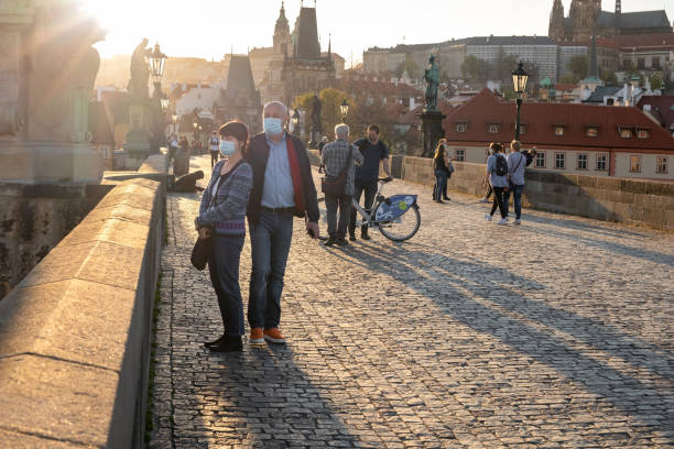 Half-empty Charles Bridge during the coronavirus pandemic, with people wearing face masks Prague, Czech Republic - April  16, 2020: Half-empty Charles Bridge during the coronavirus pandemic, with people wearing face masks charles bridge photos stock pictures, royalty-free photos & images
