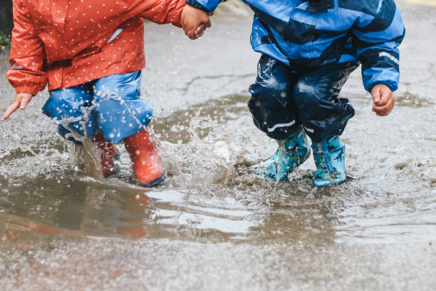 istock Kids holding hands jumping in the puddle 1222180493