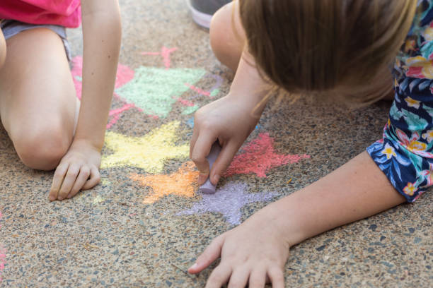 istock Sisters Doing Chalk Art On Driveway 1222180717